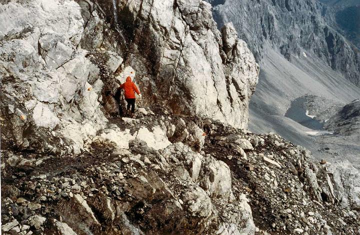 br86_schesaplana5_aa.jpg - Siv on her way back on Südwandsteig. Kind of tricky finding a foothold sometimes.when there isn't even a cable to hold on to. The mountain range next to Gemslücke in the background with the downward rush of scree. Next to impossible to walk on.